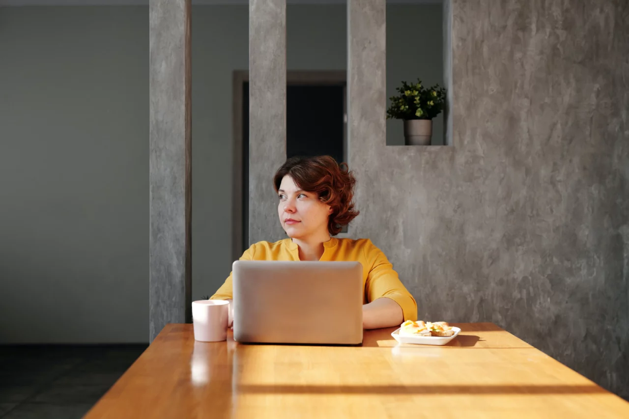 A female internal communicator sits at her desk and looks into distance as she ponders the future of internal communicaitons